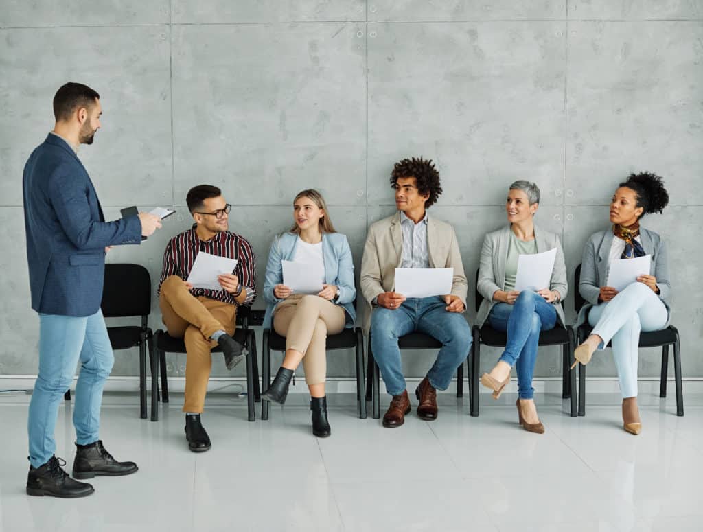 Entretien d'embauche, candidats assis avec documents.
