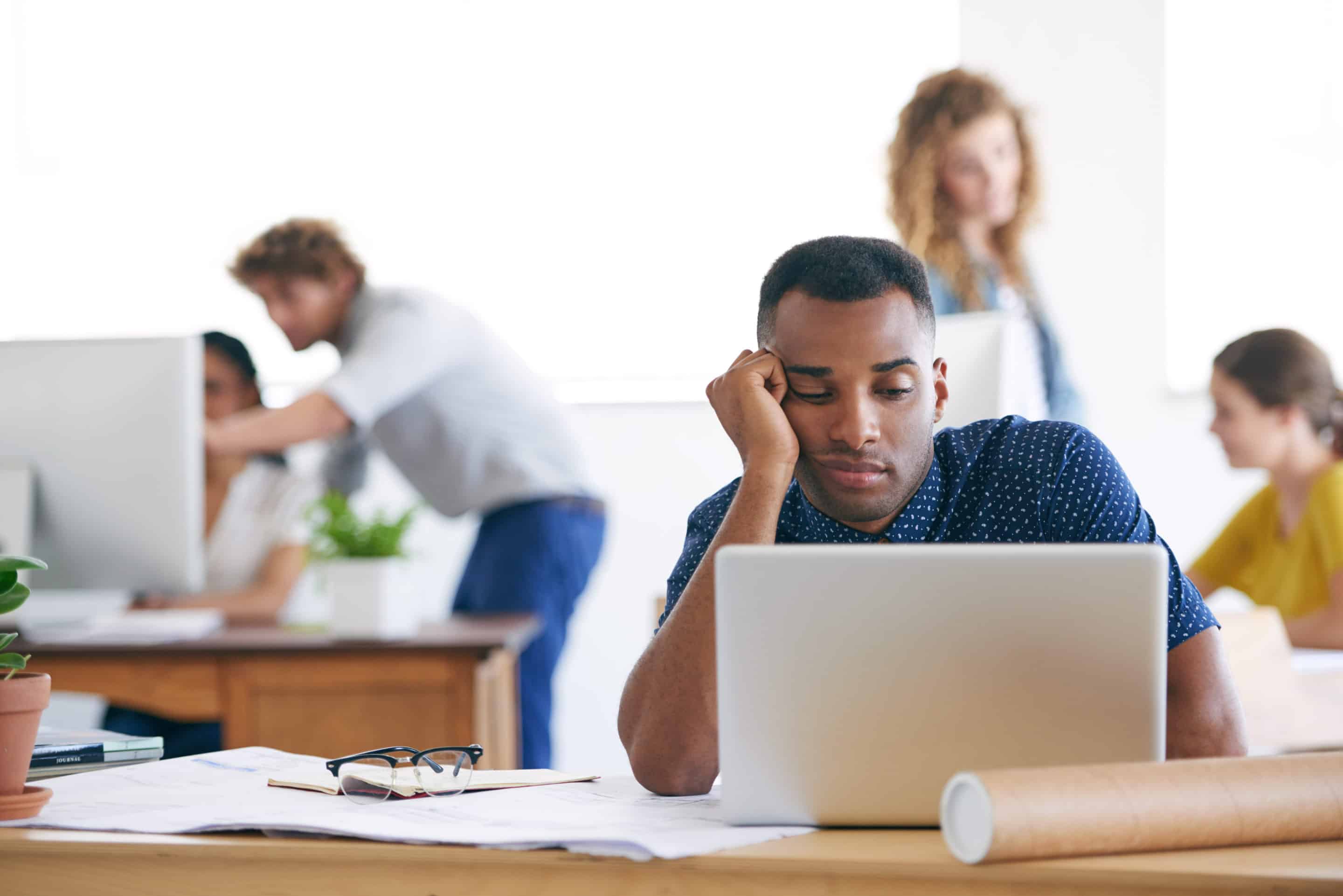 Homme pensif devant son ordinateur au bureau.