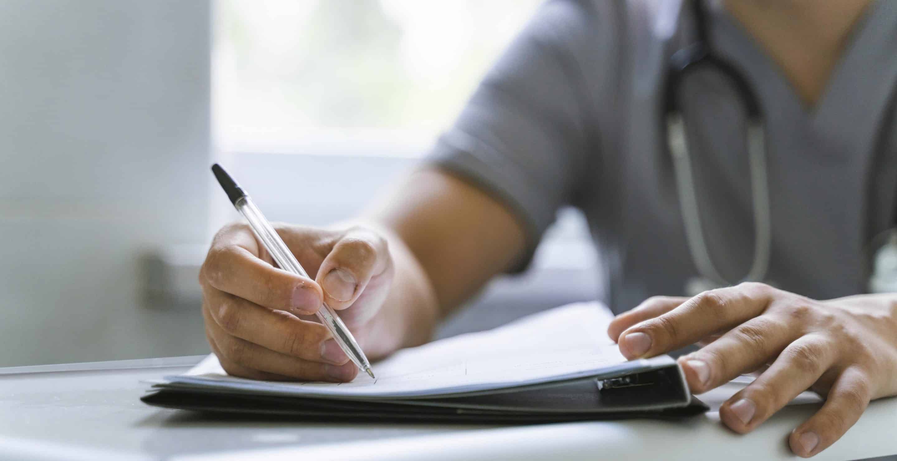 Docteur écrivant notes sur une feuille de papier.