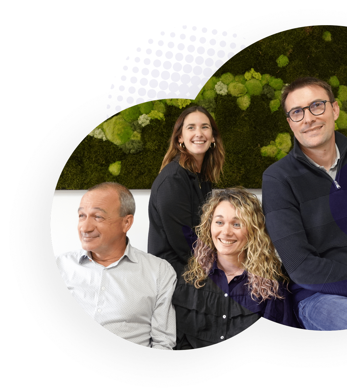 Groupe souriant devant un mur végétal.