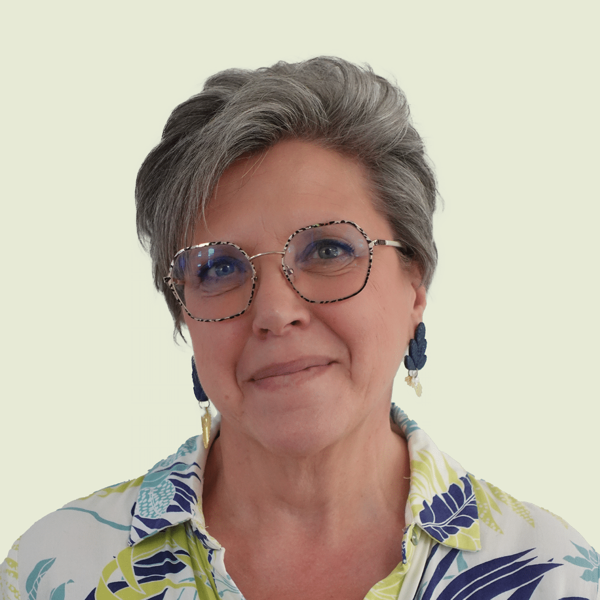 Femme souriante portant des lunettes et des boucles d'oreilles.