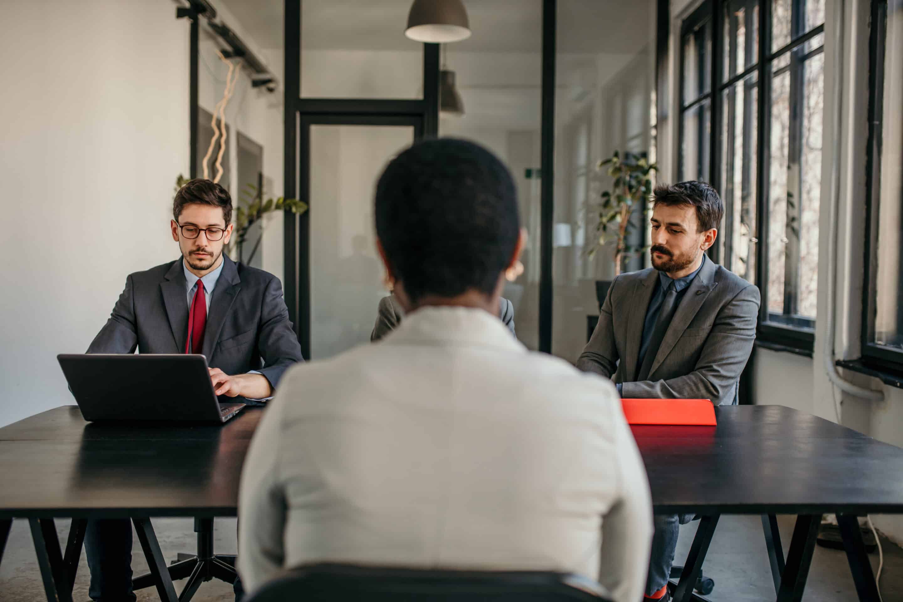 Entretien d'embauche avec trois recruteurs en costume.