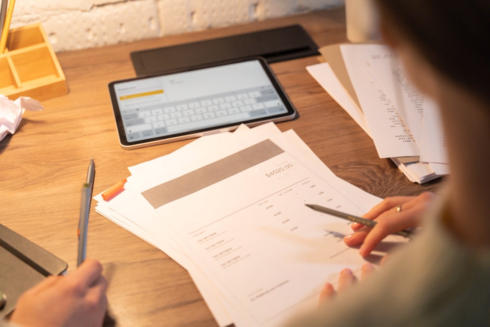 Personne travaillant sur des documents et tablettes.